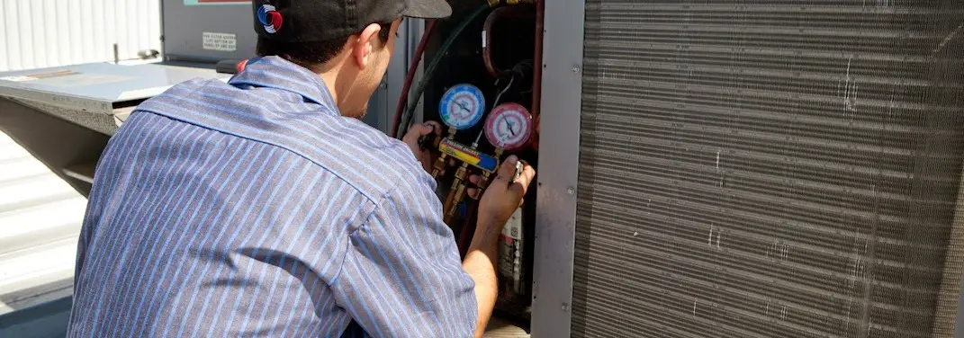 HVAC technician servicing a condenser unit in Bridge City